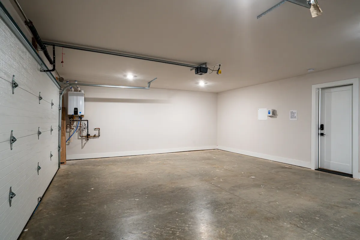 This image captures a functional garage with the garage door, an exterior door, and a water heater in view, providing a practical first impression of the secure entry point into the home.