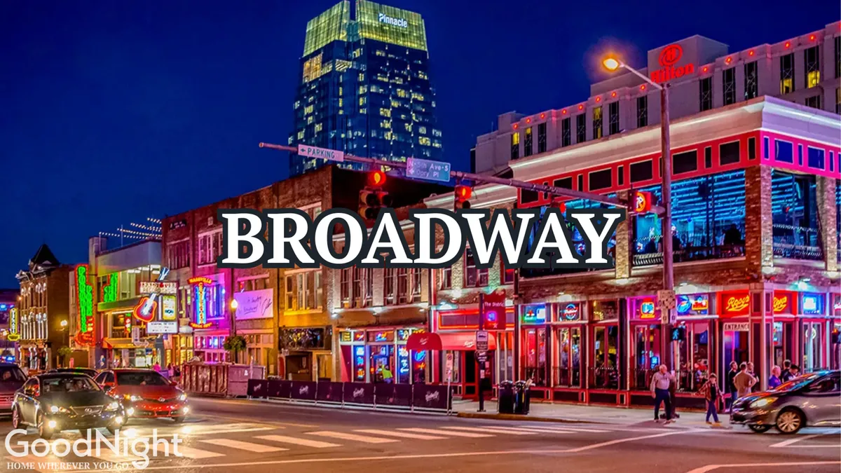 A bustling downtown Nashville street at night, illuminated by neon signs and alive with crowds, restaurants, and music venues, capturing the excitement and energy of Broadway nightlife.