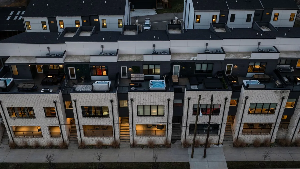 This image features a sophisticated rooftop with modern hot tubs and architectural lines, set against the backdrop of the city. The scene radiates evening charm and invites relaxation, socializing, and appreciation of the urban skyline.