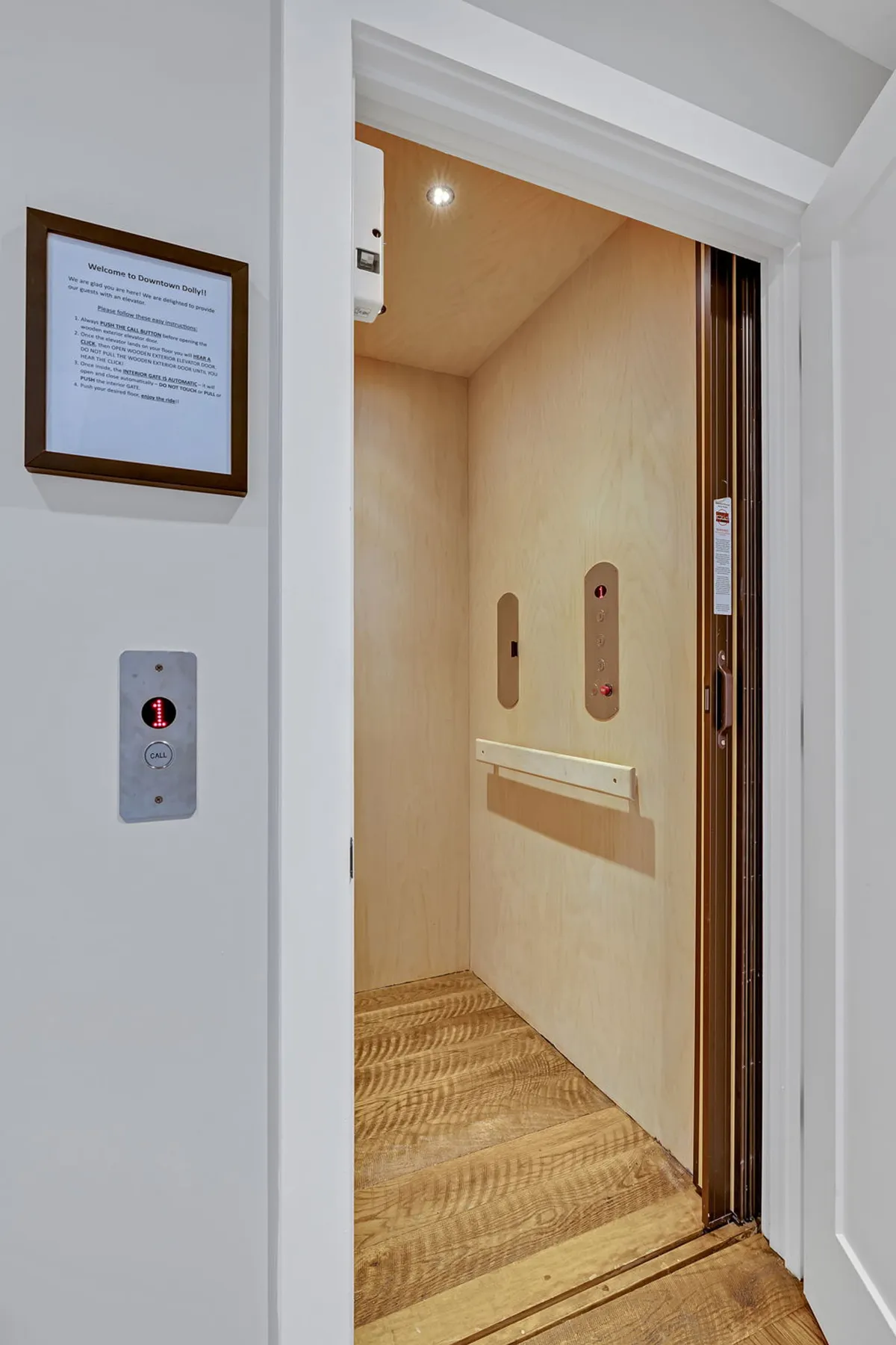 A close-up view of the in-home elevator door with its control panel and a welcoming sign, conveying convenience and accessibility within the residence.