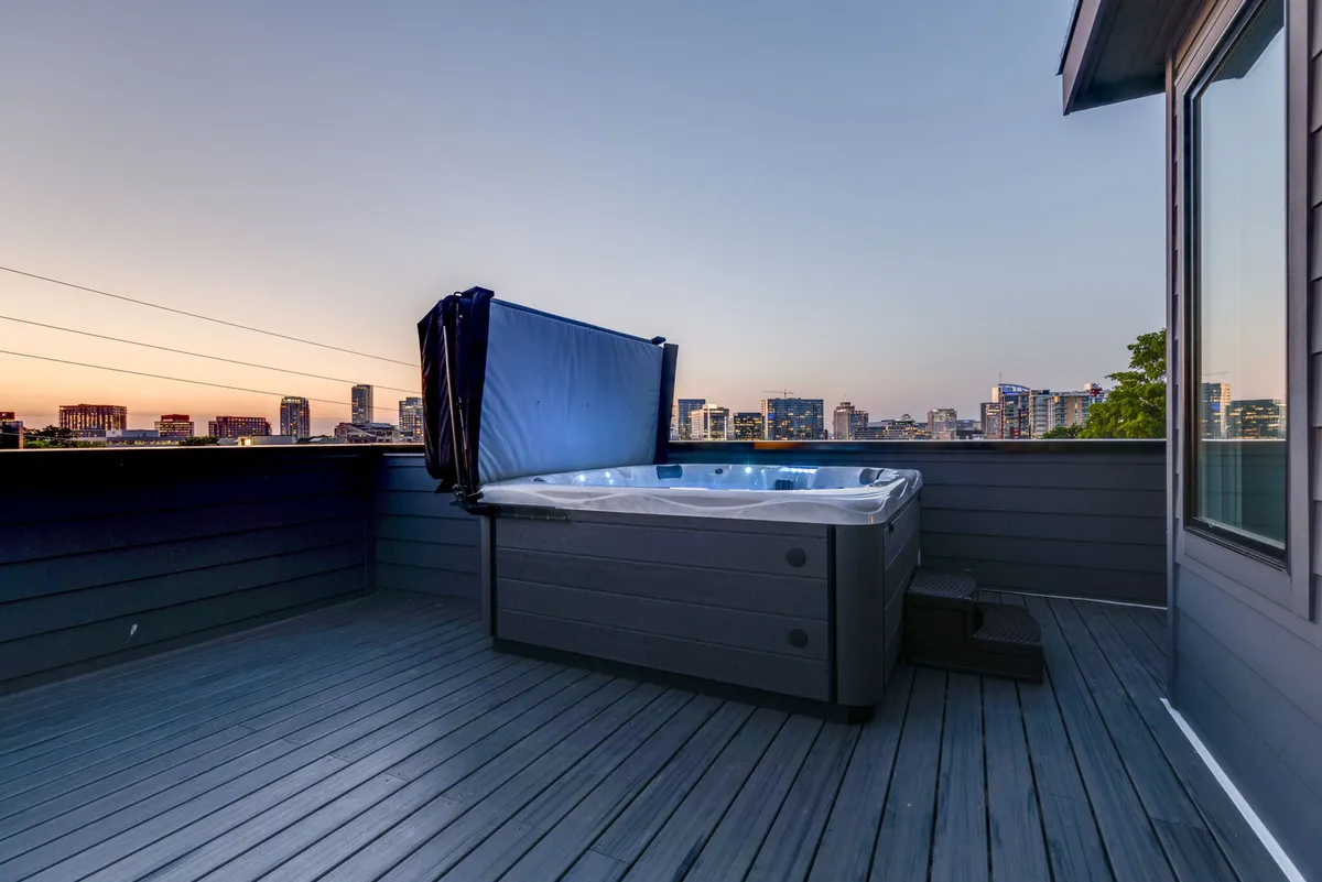 A rooftop hot tub takes center stage with unobstructed views of the city skyline from the deck. The serene and open atmosphere is perfect for unwinding after a day in the city, offering a tranquil escape with the benefits of both warm water and inspiring vistas.